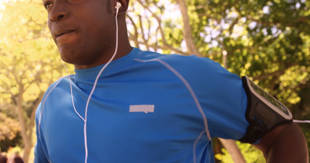 Man Running Outdoors with Armband and Earphones - Free Images, Stock Photos and Pictures on Pikwizard.com