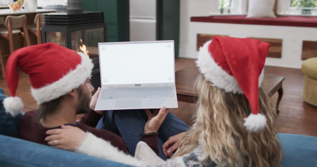 Couple with Santa Hats Relaxing with Laptop During Christmas Season - Free Images, Stock Photos and Pictures on Pikwizard.com