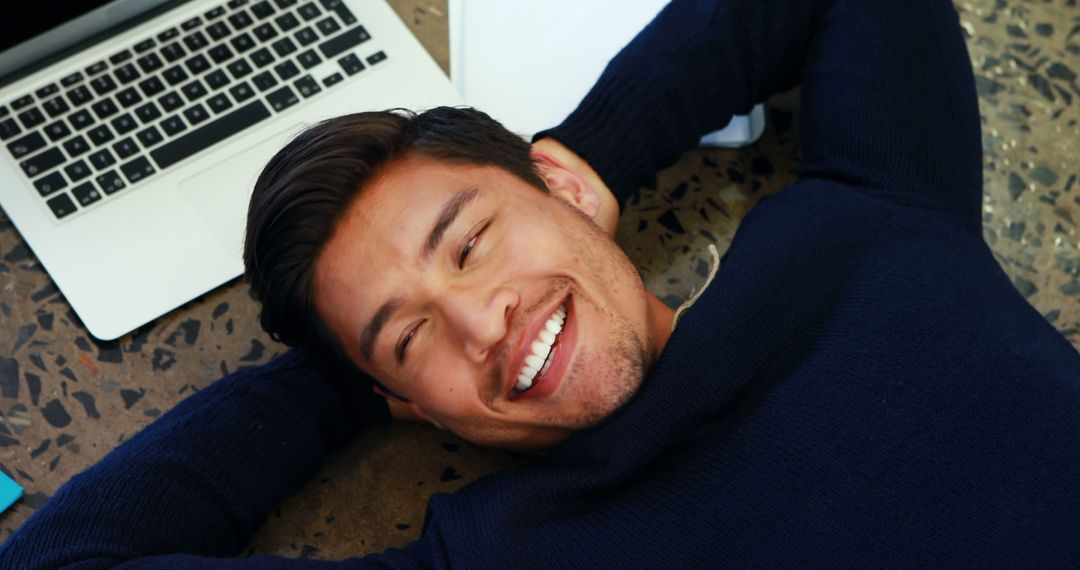 Smiling Young Man Relaxing Next to Laptop - Free Images, Stock Photos and Pictures on Pikwizard.com