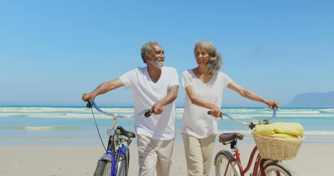 Senior Couple Enjoying Relaxing Beach Walk with Bicycles