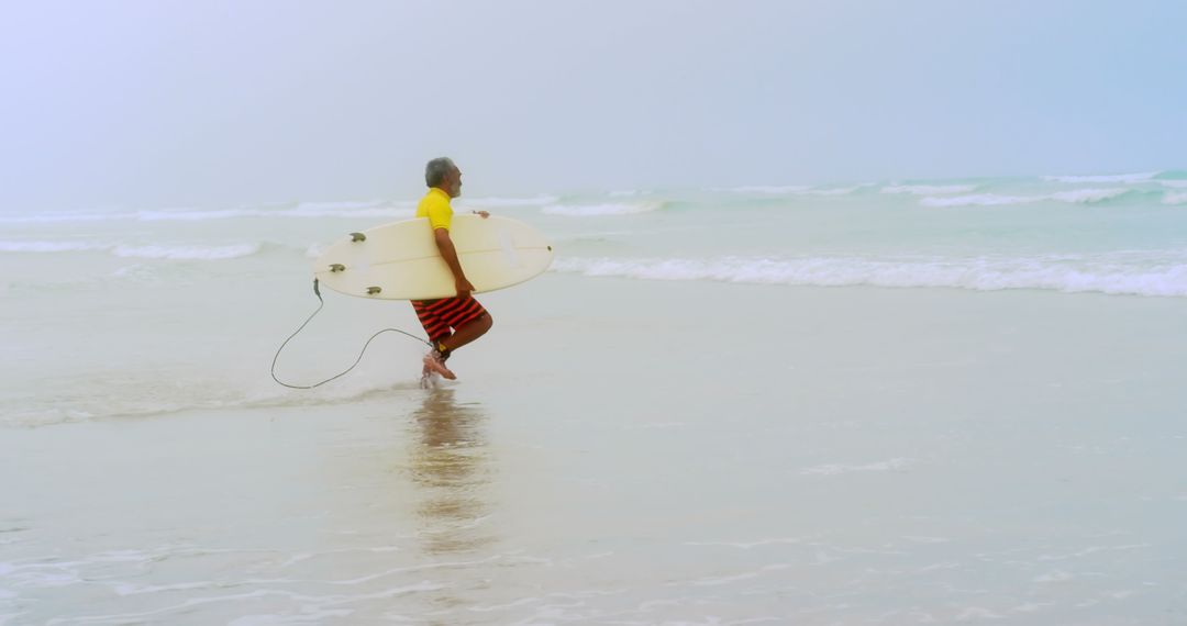 Senior African American Surfer Running with Surfboard Towards Ocean Waves