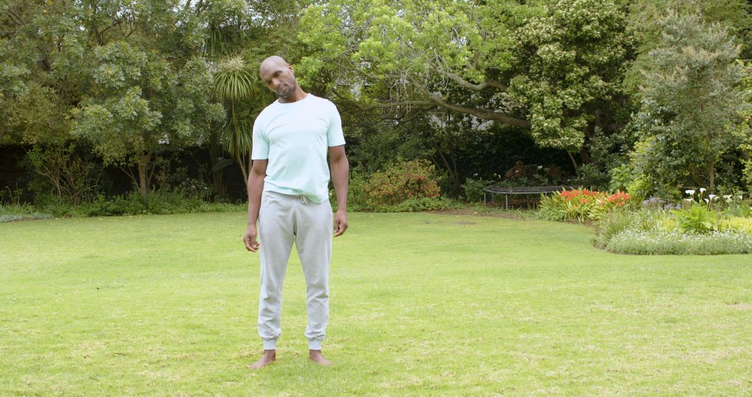 Barefoot Man Exercising Neck Under Trees in Garden