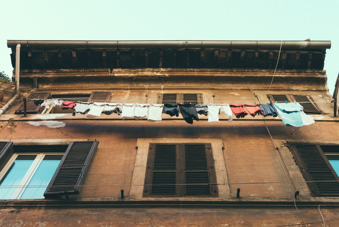 Clothes Hanging to Dry on a Rustic Building Facade - Free Images, Stock Photos and Pictures on Pikwizard.com