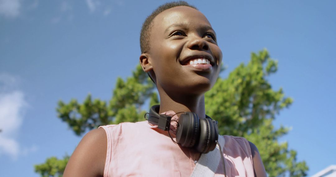 Happy Young Woman with Headphones Enjoying Sunny Day Outdoors - Free Images, Stock Photos and Pictures on Pikwizard.com