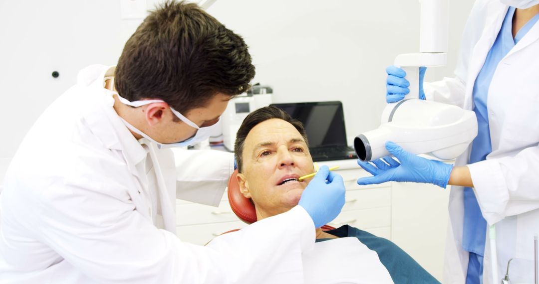 Dentist Treating Middle-Aged Man with Dental Equipment - Free Images, Stock Photos and Pictures on Pikwizard.com