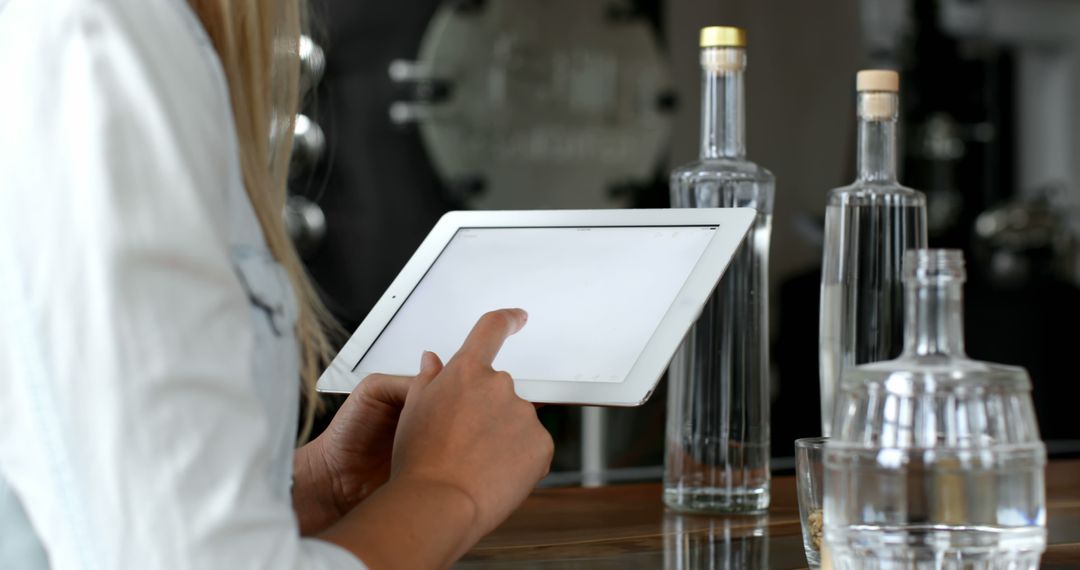 Person Using Tablet in Bar Area with Bottles - Free Images, Stock Photos and Pictures on Pikwizard.com