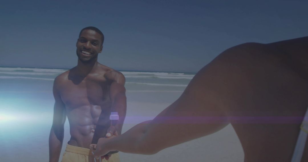 Shirtless Man Smiling While Holding Hands on Sunny Beach