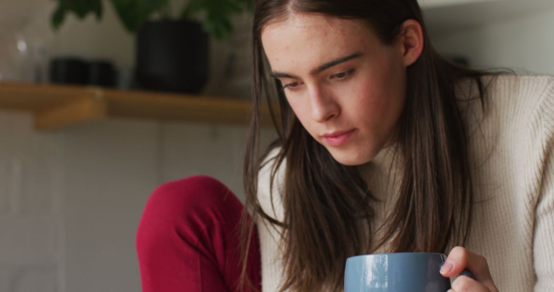 Caucasian non-binary transgender woman drinking coffee and using smartphone - Free Images, Stock Photos and Pictures on Pikwizard.com