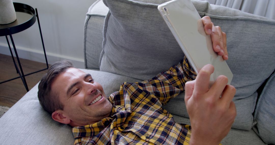 Man Smiling While Using Tablet on Sofa at Home - Free Images, Stock Photos and Pictures on Pikwizard.com