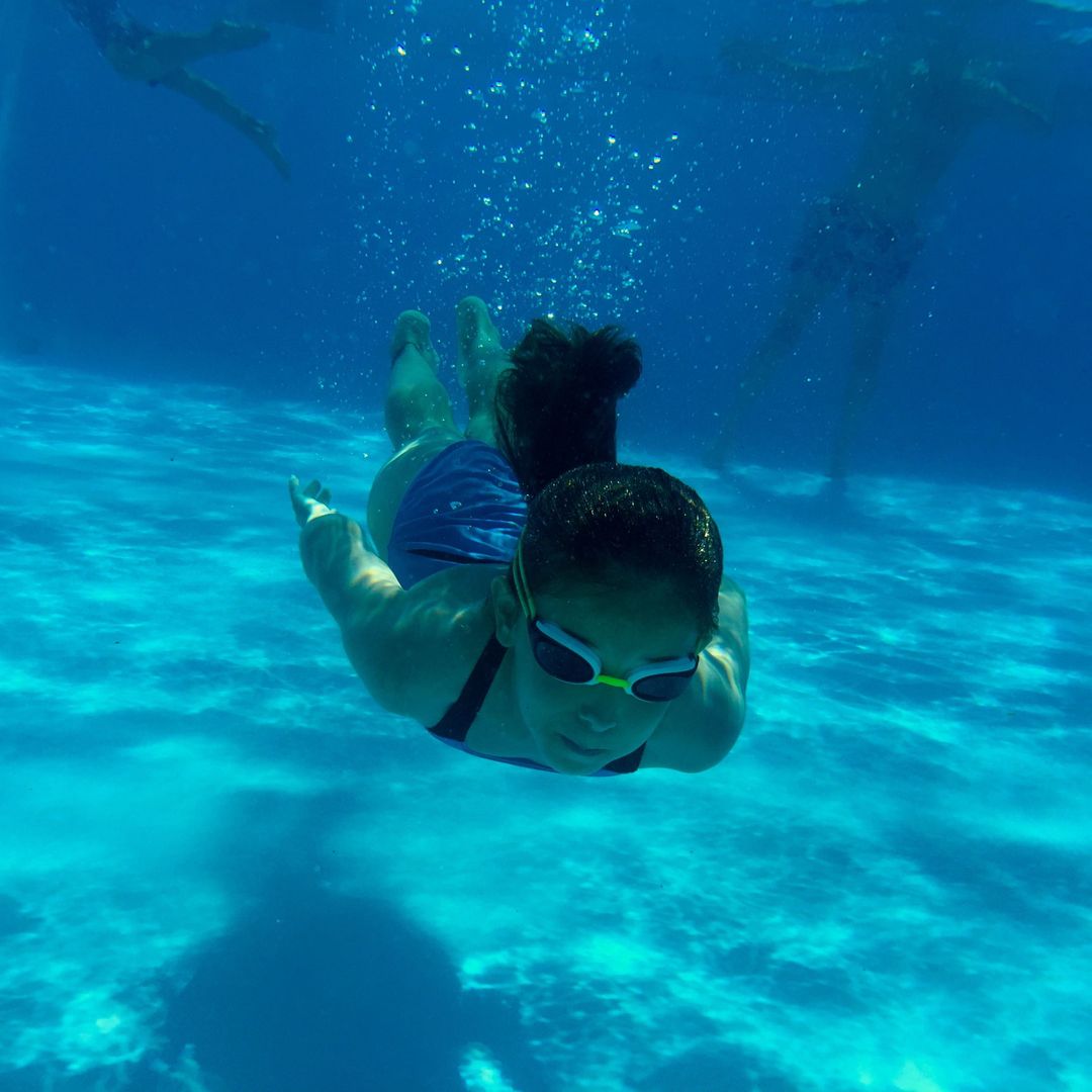 Woman Swimming Underwater with Goggles in Blue Pool - Free Images, Stock Photos and Pictures on Pikwizard.com
