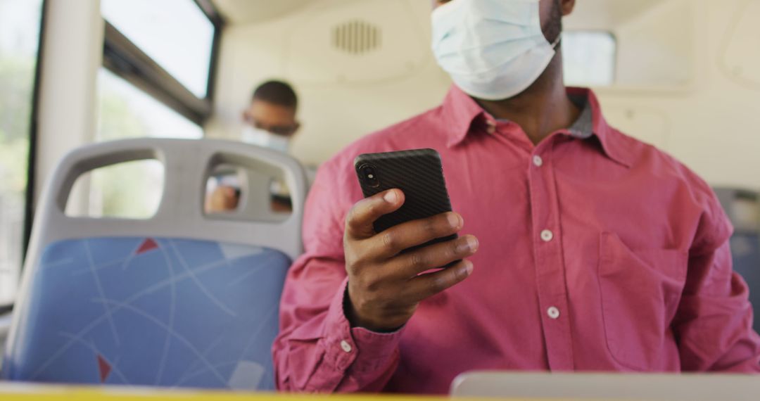Man in Mask Using Smartphone While Traveling on Bus during Pandemic