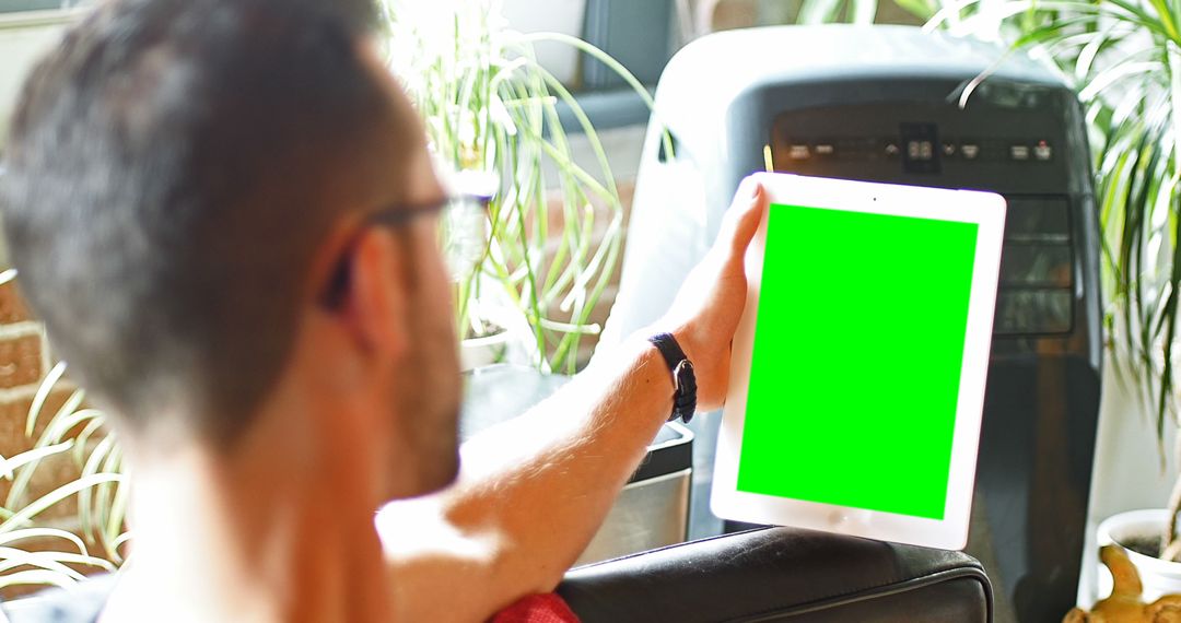 Man Holding Tablet with Green Screen in Modern Home Interior - Free Images, Stock Photos and Pictures on Pikwizard.com