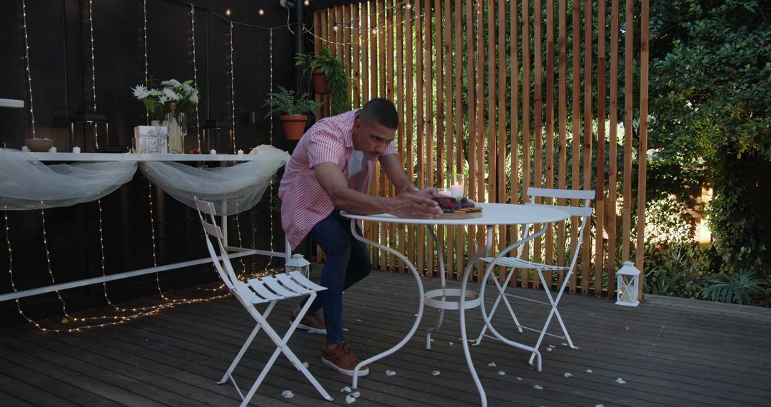 Man Preparing Outdoor Table for Cozy Evening Gathering