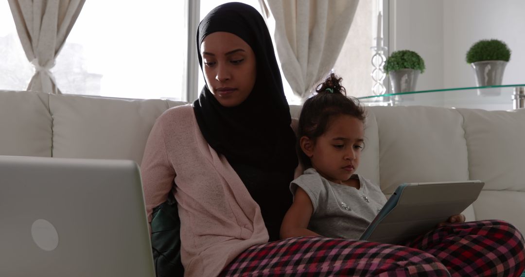 Mother and Daughter Using Devices on Sofa