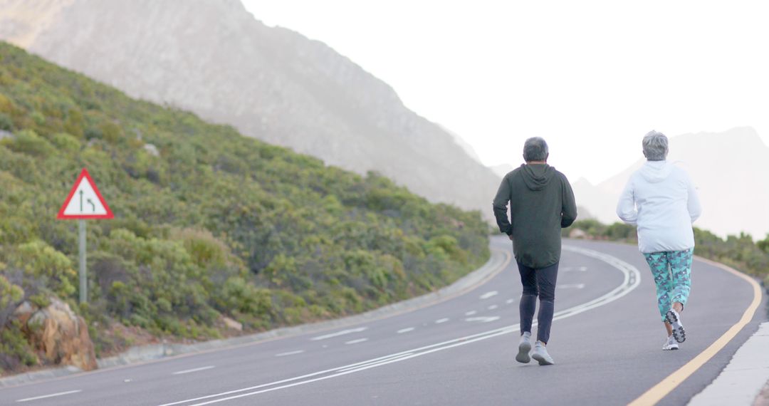 Senior Couple Jogging on Scenic Mountain Road - Free Images, Stock Photos and Pictures on Pikwizard.com