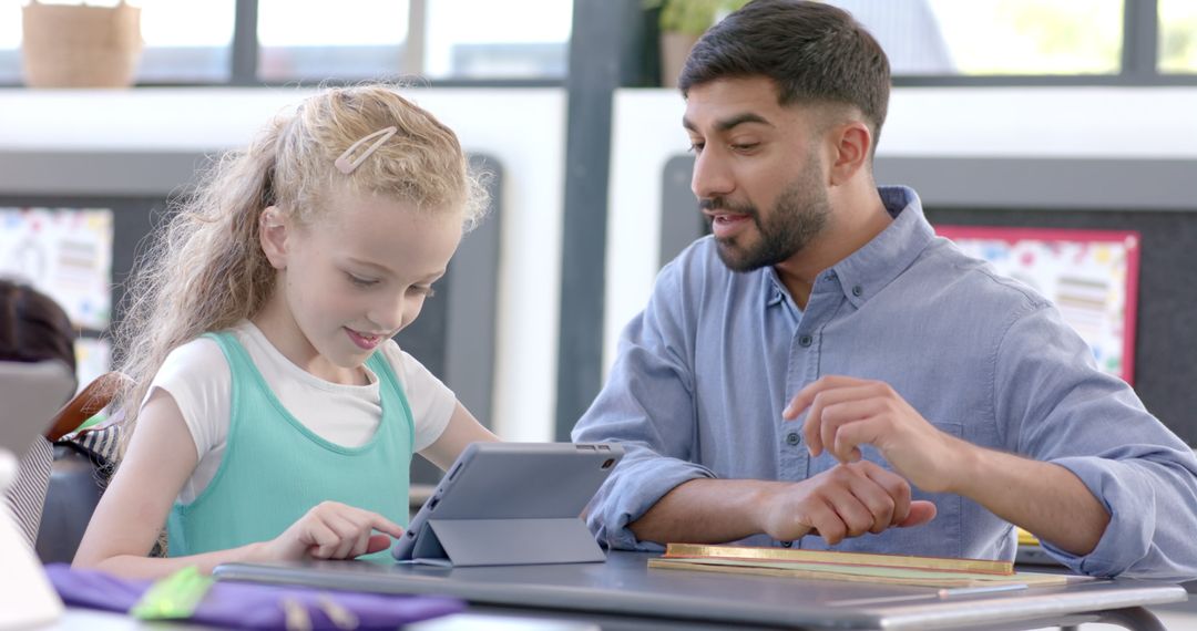 Teacher Guiding Student with Tablet Technology in Classroom