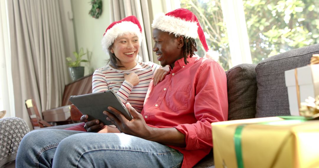 Diverse Couple Celebrating Christmas with Hats and Tablet - Free Images, Stock Photos and Pictures on Pikwizard.com