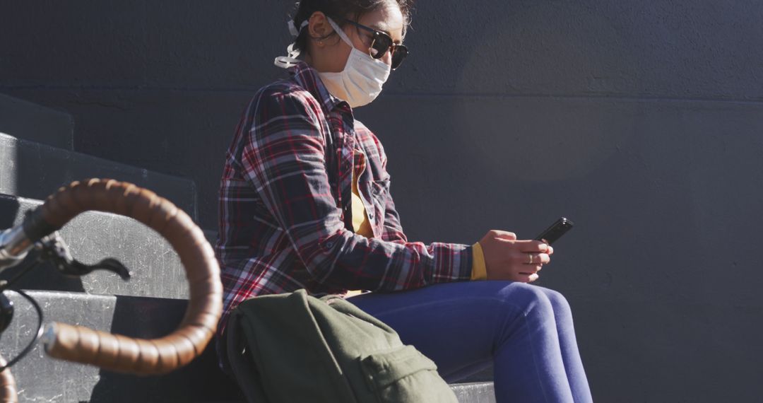 Woman Wearing Mask Sitting on Steps Using Smartphone - Free Images, Stock Photos and Pictures on Pikwizard.com