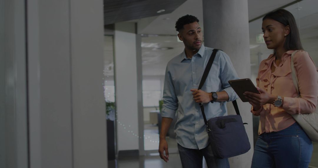 Two colleagues walking and consulting tablet in modern office corridor for agile teamwork