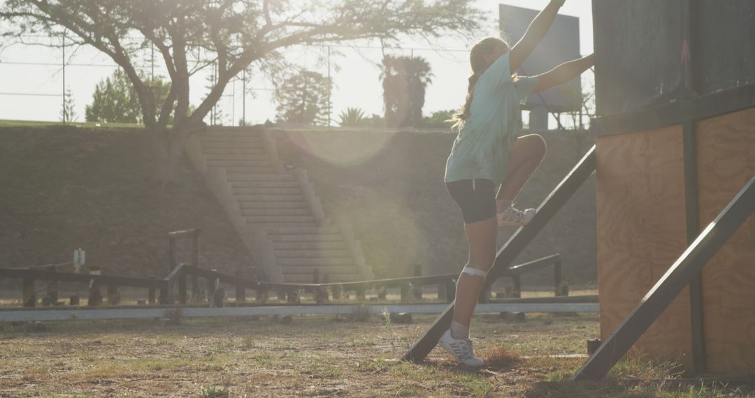 Determined Girl Climbing Obstacle Course Wall at Bootcamp