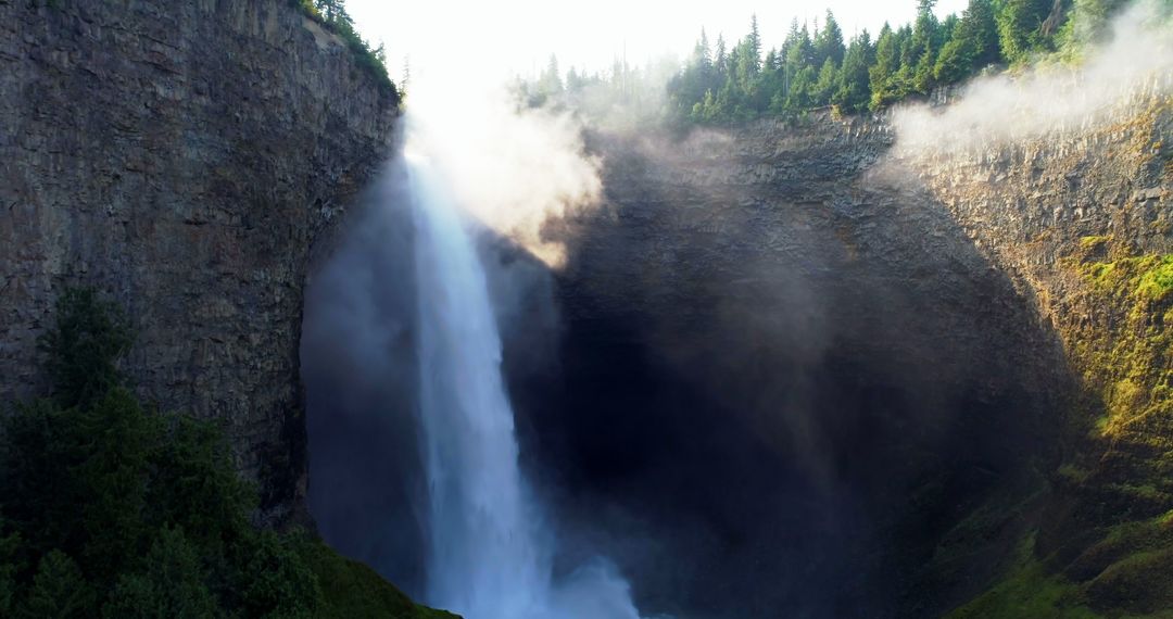 A waterfall's serene yet powerful beauty mesmerizes amidst a verdant, misty backdrop. - Free Images, Stock Photos and Pictures on Pikwizard.com