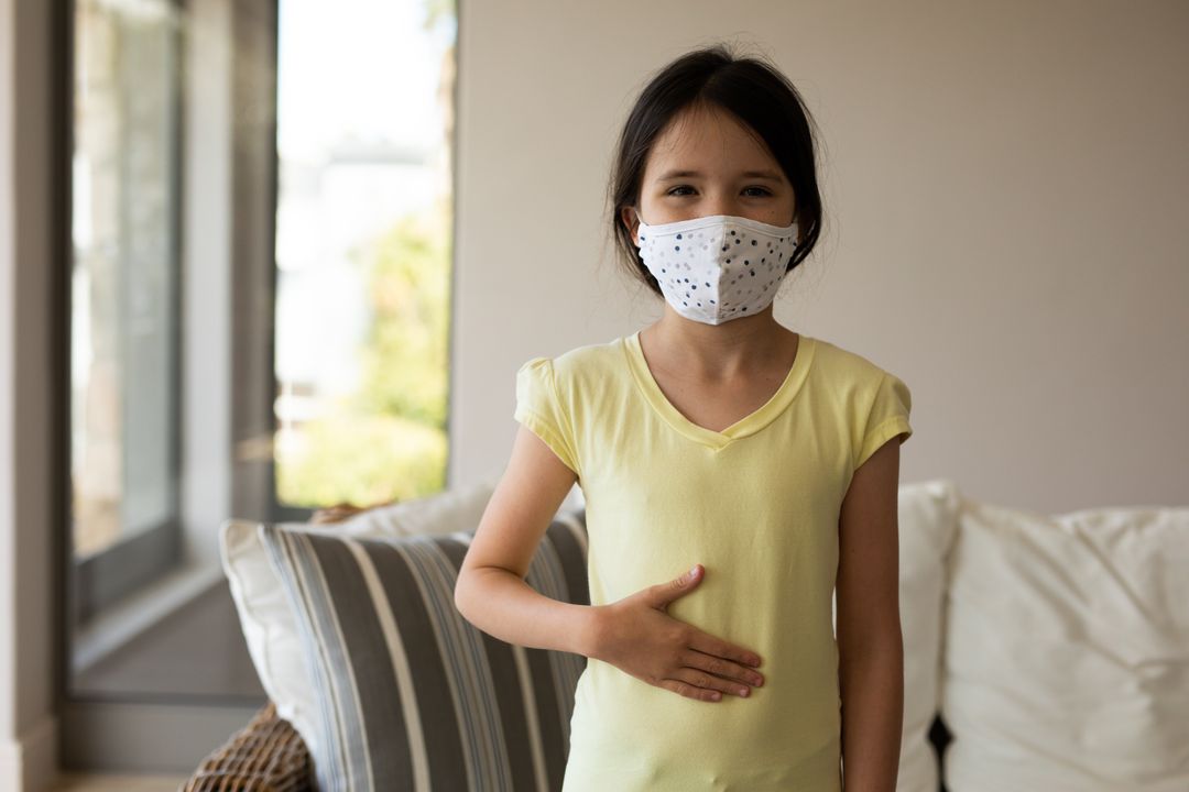 Young Girl Wearing Face Mask Touching Stomach Indoors - Free Images, Stock Photos and Pictures on Pikwizard.com