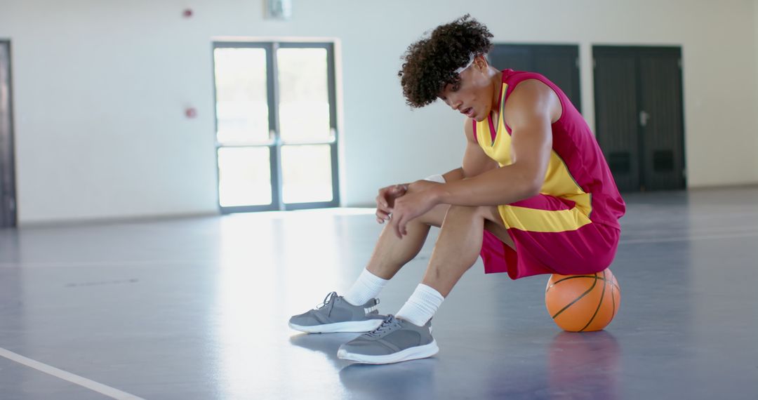 Defeated Basketball Player Sitting Dejected on Court
