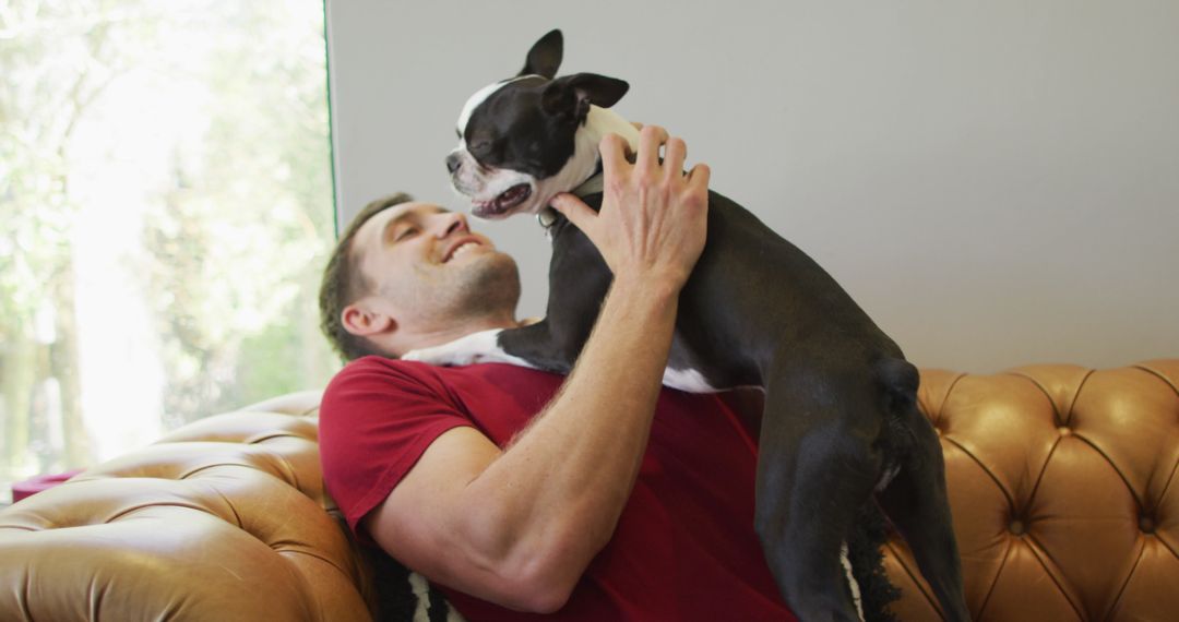 Joyful Man Bonding with Dog on Sofa at Home