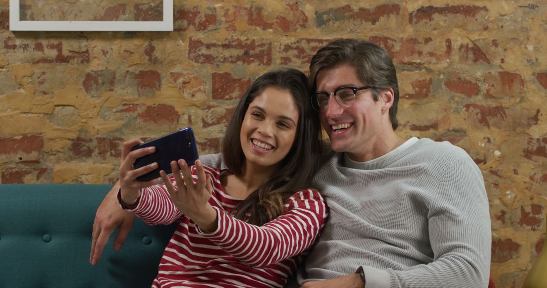 Couple Taking Selfie on Couch Against Brick Wall - Free Images, Stock Photos and Pictures on Pikwizard.com