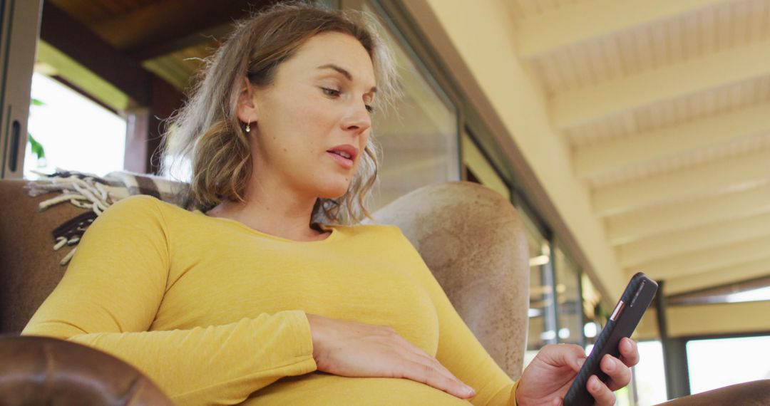 Pregnant Woman Relaxing While Using Smartphone at Home