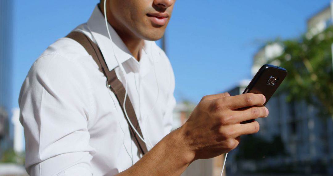 Businessman Listening to Music on Smartphone While Walking Outdoors - Free Images, Stock Photos and Pictures on Pikwizard.com