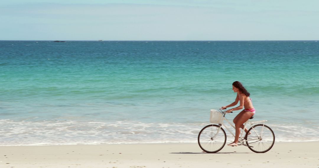 Woman Riding Bicycle on Sunlit Beach by Turquoise Ocean Water - Free Images, Stock Photos and Pictures on Pikwizard.com