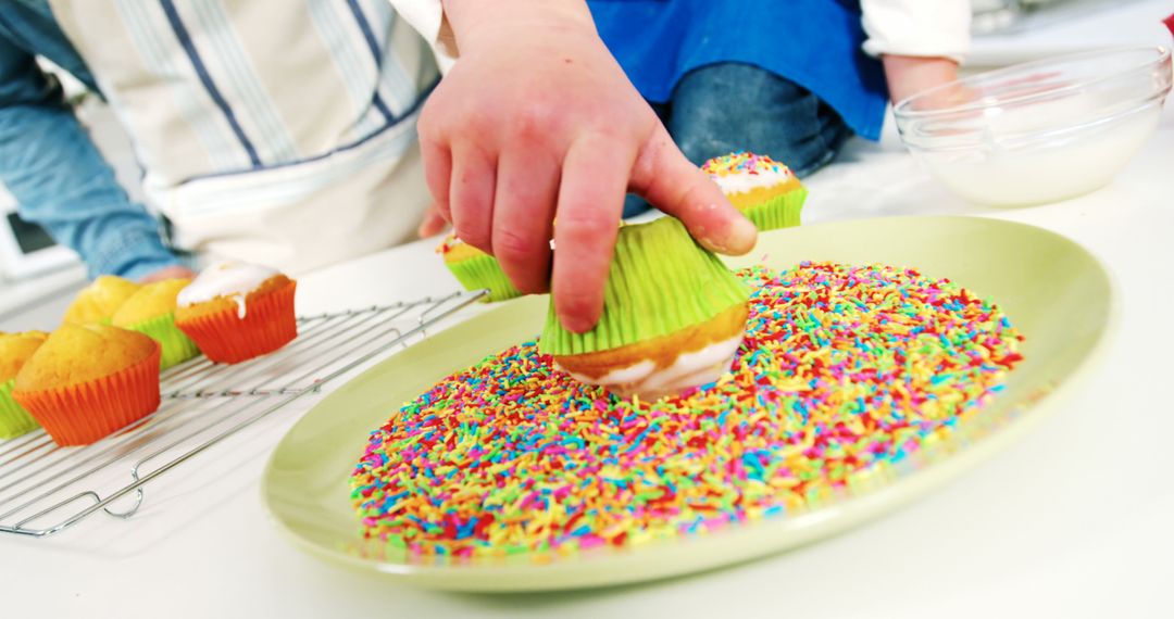 Child Decorating Cupcakes with Colorful Sprinkles on Kitchen Plate - Free Images, Stock Photos and Pictures on Pikwizard.com