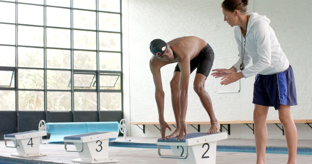 Coach Instructs Swimmer on Diving Technique in Indoor Pool