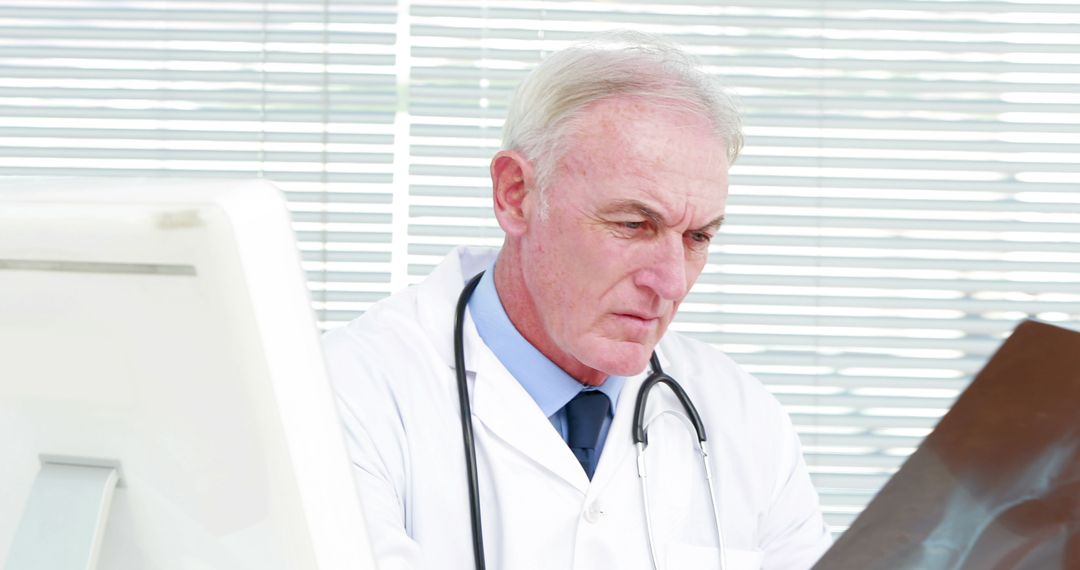 Elderly doctor reviewing medical imaging results in office - Free Images, Stock Photos and Pictures on Pikwizard.com