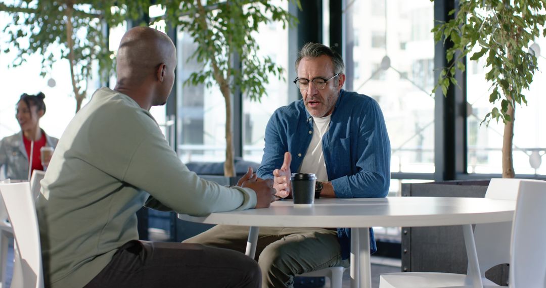 Multiracial colleagues discussing ideas over coffee in modern coworking lounge
