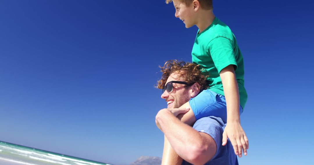 Father Giving Son Piggyback Ride on Sunny Beach Day - Free Images, Stock Photos and Pictures on Pikwizard.com