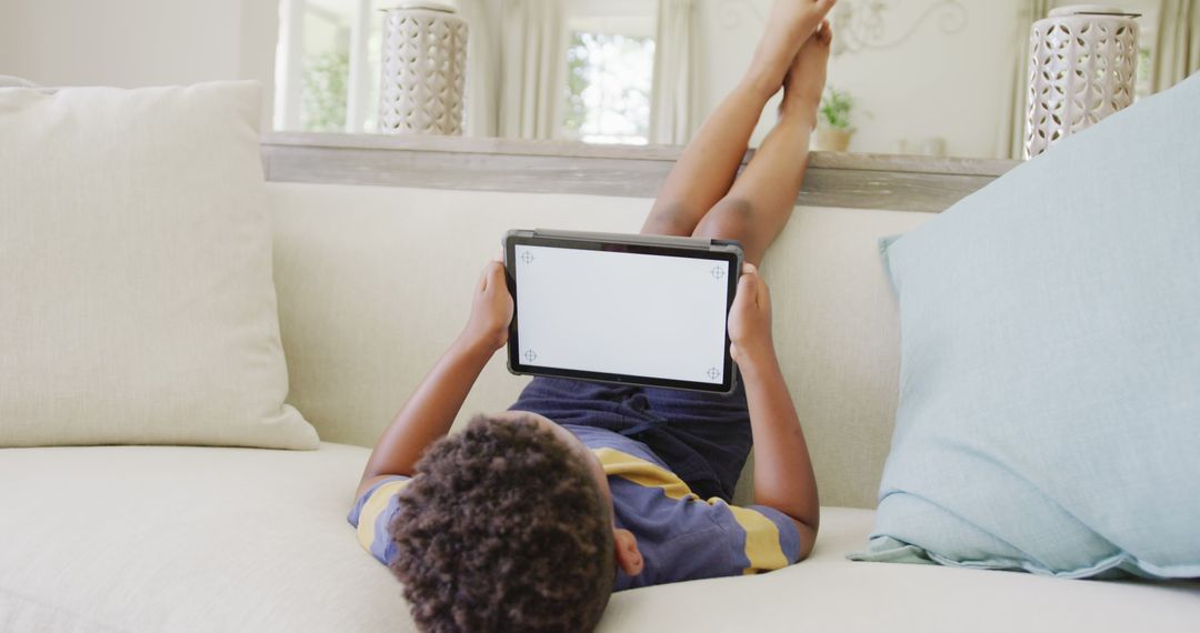 Young Boy Using Tablet on Couch in Living Room - Free Images, Stock Photos and Pictures on Pikwizard.com