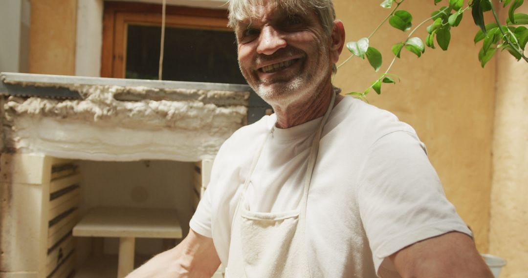 Smiling Senior Man Handling Pottery in Workshop
