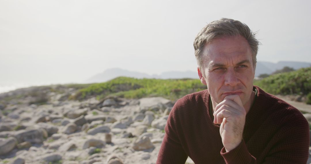 Thoughtful Man Contemplating on a Rocky Beach - Free Images, Stock Photos and Pictures on Pikwizard.com