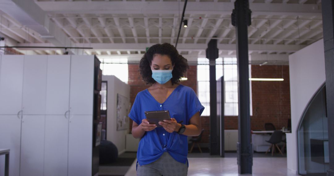 Young Woman Wearing Mask Using Digital Tablet in Modern Office Space - Free Images, Stock Photos and Pictures on Pikwizard.com