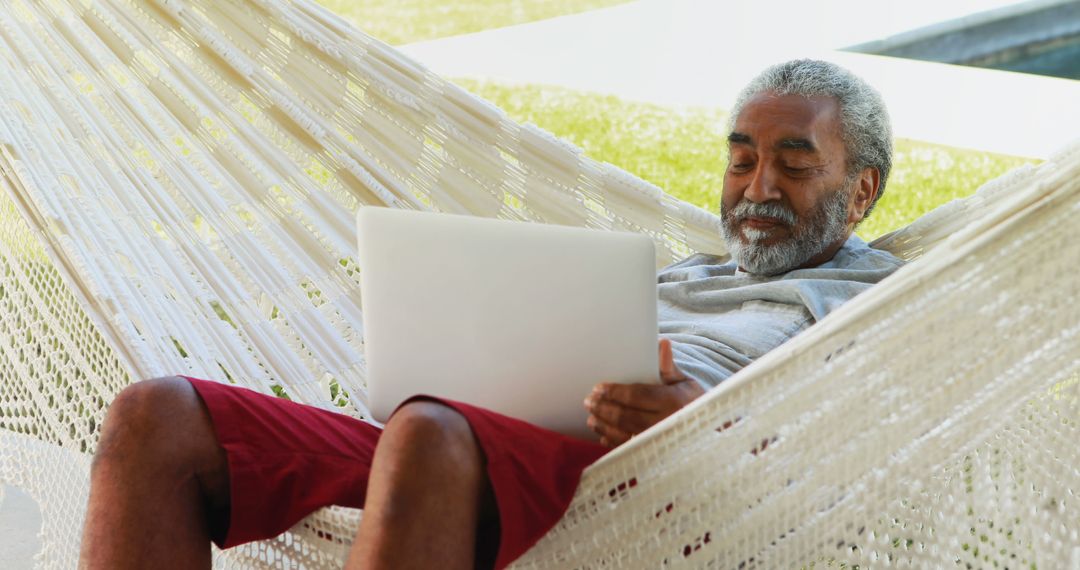 Senior Man Relaxing in Hammock with Laptop Outdoors - Free Images, Stock Photos and Pictures on Pikwizard.com