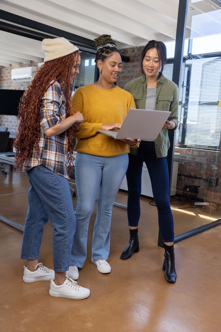Diverse Female Colleagues Discussing Project on Laptop in Open Office