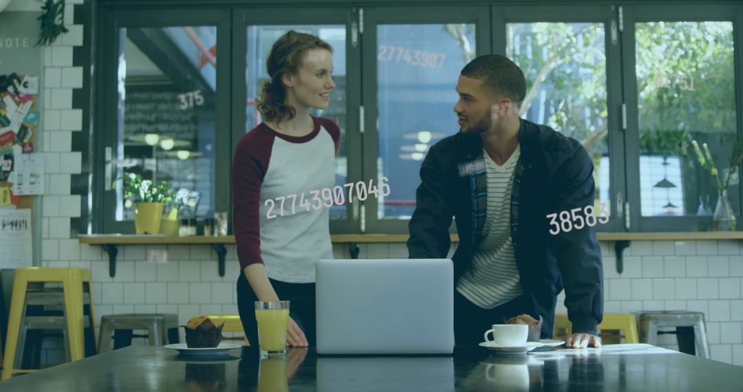 Two Colleagues Discussing Project Using Laptop in Contemporary Cafe