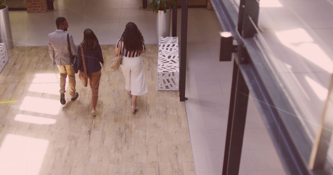 Business professionals walking and collaborating in modern office corridor carrying bags