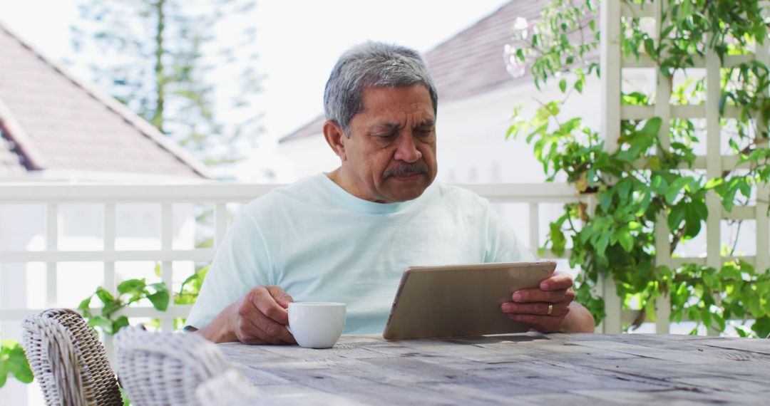 Senior Man Reading Digital Tablet While Drinking Coffee on Porch - Free Images, Stock Photos and Pictures on Pikwizard.com