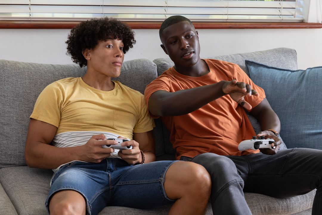 Diverse Friends Gaming on Sofa with Game Controllers