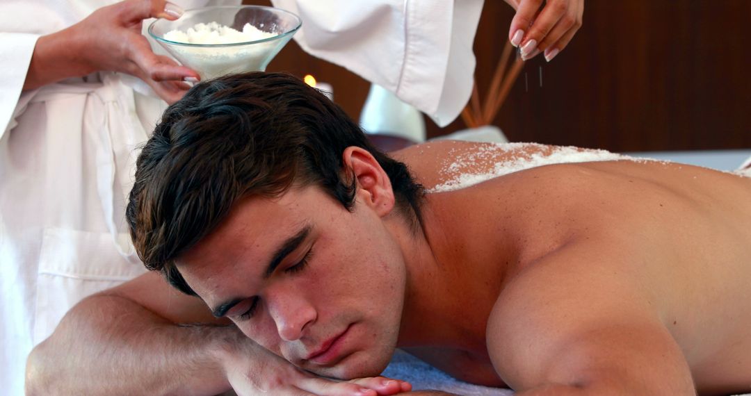 Handsome man getting a salt scrub treatment at the spa - Free Images, Stock Photos and Pictures on Pikwizard.com