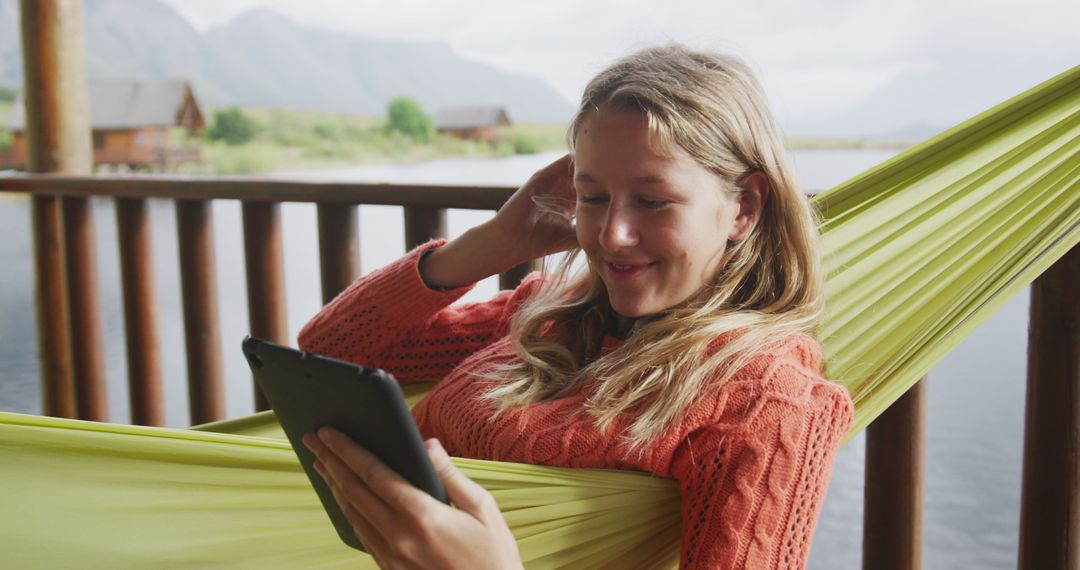 Woman Relaxing in Hammock by Lake Holding Tablet - Free Images, Stock Photos and Pictures on Pikwizard.com