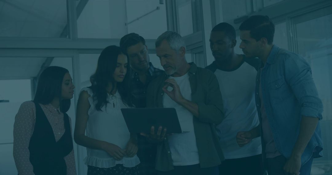 Diverse Team Collaborates on Laptop in Modern Office Environment